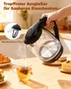 A glass electric kettle is pouring hot water into a mug with a tea bag, with pastries in the background. Produktbild-Vorschau