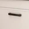 A close-up shot of a black handle on a white cabinet door. Podgląd zdjęcia produktu