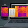 A thermal camera attached to a smartphone and a laptop displaying thermal imaging. Voir les images du produit