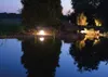 A garden pond at dusk, illuminated by a spherical garden light. Voir les images du produit