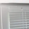 Close-up view of a white aluminum venetian blind installed in a window frame. Produktbild-Vorschau