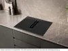 A modern kitchen countertop with a black induction hob and integrated extractor fan. Produktbild-Vorschau