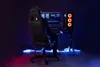 A person is sitting in a gaming chair in front of a computer setup, with neon lighting. Produktbild-Vorschau