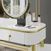 A close-up view of a white vanity table with gold accents, featuring a makeup palette, brushes, and various cosmetic bottles. Náhled obrázku produktu
