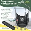 A dark gray hanging chair with pillows and a bottle holder, set against a blurred outdoor background with greenery and a railing. Produktbild-Vorschau
