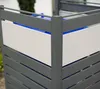 Close-up view of a modern metal trash can enclosure with white panels and gray slats, showing the blue interior of a trash bin. Náhled obrázku produktu
