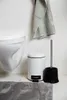 A bathroom scene with a toilet, trash can, toilet brush, and bath mat. Anteprima dell’immagine prodotto