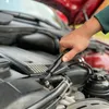 A person's hand is using a torque wrench to work on a car engine. Voir les images du produit