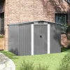 A gray metal garden shed is shown in front of a brick house with green grass and a stone path in the foreground. Náhled obrázku produktu