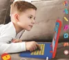 A young boy is lying on a couch and playing with a toy laptop. Anteprima dell’immagine prodotto
