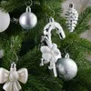 Close-up of various silver and white Christmas tree ornaments hanging on a green Christmas tree. Produktbild-Vorschau