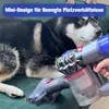 A dog is lying on a green surface next to a handheld vacuum cleaner attachment. Produktbild-Vorschau