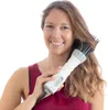 A woman is using a hair dryer with a brush attachment. Náhled obrázku produktu