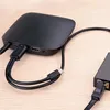 A close-up view of a black Ugreen adapter connected to cables on a wooden surface. Voir les images du produit