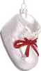 A white glass baby shoe ornament with a red glitter bow. Voir les images du produit