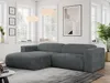A modern living room with a dark gray corduroy sectional sofa as the main focus, placed on a rug in front of a window and a piece of abstract art.