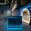 A modern bar interior with a illuminated counter, shelves stocked with bottles, and bar stools. Anteprima dell’immagine prodotto