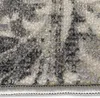 A close-up view of a carpet with a grey, white, and cream abstract pattern, showing the texture of the fibers and the stitched edge. Produktbild-Vorschau