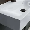 A close-up view of a modern white ceramic sink with a black drain cover. Produktbild-Vorschau