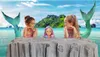 Two young girls dressed as mermaids with mermaid tails, posing with a doll in the water. Voir les images du produit