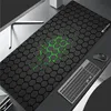 A gaming mousepad with a hexagonal pattern and green accents, placed on a desk with a keyboard and mouse. Náhled obrázku produktu