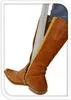 A close-up of a person's leg wearing a brown leather boot with a silver shoehorn inserted. Podgląd zdjęcia produktu