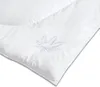 A close-up, angled view of a white comforter with an embroidered leaf pattern. Produktbild-Vorschau
