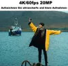 A woman in a yellow jacket takes a selfie with a boat in the background. Produktbild-Vorschau