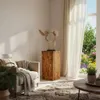 A living room scene with a wooden pedestal, a chair, a rug, and a window overlooking a garden. Voir les images du produit