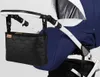 A black organizer bag is attached to the handle of a blue and white stroller. Náhľad obrázku produktu