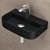 A black ceramic sink with a chrome faucet against a textured wall. Produktbild-Vorschau