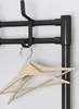 A close-up view of a black metal coat rack with two wooden hangers hanging from it. Náhled obrázku produktu