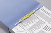 A close-up shot of a blue file folder open, with documents and a yellow and gray binding mechanism inside. Anteprima dell’immagine prodotto