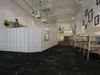 Interior of a modern cafe with a white tiled counter and black marble flooring. Produktbild-Vorschau