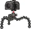 A black JOBY GorillaPod tripod with a black Olympus camera mounted on top, set against a white background. Produktbild-Vorschau