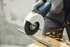 A person wearing gloves is using a Festool angle grinder to cut a metal rod, with sparks flying. Produktbild-Vorschau