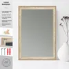 A mirror with a decorative frame is displayed on a white surface, with a vase and dried flowers to the right. To the left, there is a graphic overlay with product information and images of mounting hardware. Produktbild-Vorschau