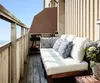 A balcony with a sofa, cushions, and plants, overlooking the sea. Produktbild-Vorschau