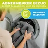 A person is putting a grey blanket into a washing machine. Produktbild-Vorschau