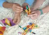 Two people are shown with a pile of colorful pens and some cards. Anteprima dell’immagine prodotto
