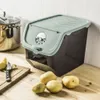A potato and onion storage box with potatoes and a knife on a wooden cutting board in a kitchen setting. Produktbild-Vorschau
