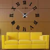A large DIY Roman numeral wall clock is mounted on a brown tiled wall above a bright yellow sofa. Produktbild-Vorschau