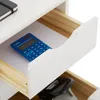 A close-up view of an open drawer in a white roll container, revealing a blue calculator and a black stapler in the drawer below. Produktbild-Vorschau