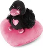 A black plush duck with pink accents sits on a pink heart-shaped pillow. Produktbild-Vorschau