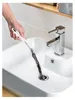 A hand is using a drain cleaning brush to remove hair from a sink drain. Produktbild-Vorschau