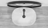 A top-down view of a white oval sink with a black faucet, placed on a wooden surface, with a black-rimmed mirror above it. Náhľad obrázku produktu