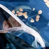 A close-up view of a blue duvet cover with a floral pattern and a white zipper. Náhled obrázku produktu