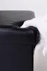 A hand in a white glove is touching the corner of a black storage ottoman. Náhled obrázku produktu