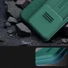 A close-up view of a green phone case with a textured back and a sliding camera cover, resting on dark, rough material. Produktbild-Vorschau