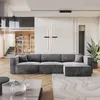 A modern living room with a large sectional sofa, a coffee table, and a bookshelf in the background. Produktbild-Vorschau